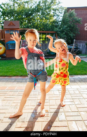 Porträt von zwei kleinen Mädchen Schwestern Spaß auf home Hinterhof. Freunde Mädchen dumme Gesichter. Lifestyle Familie Moment der Geschwister spielen toge Stockfoto