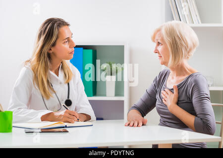 Ältere Patienten erzählen Frauen Arzt, wie Sie mit Schmerzen in der Brust. Stockfoto