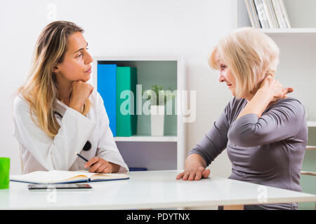 Ältere Patienten sagen, Ärztin, wie Sie hat Schmerzen im Nacken. Stockfoto