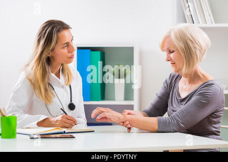 Ältere Patienten sagen, Ärztin, wie sie das Handgelenk Schmerzen. Stockfoto