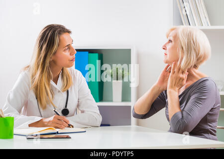 Ältere Patienten sagen, Ärztin, wie Sie Probleme mit ihrer Kehle. Stockfoto