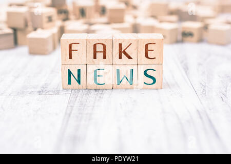 Die Worte, die gefälschte Nachrichten gebildet, die durch hölzerne Blöcke auf einem weißen Tisch Stockfoto