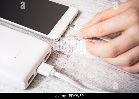 Weibliche Hand Anschließen der Bank mit PMobile Telefon Aufladen der Batterie schwach, Hohe Betrachtungswinkel Stockfoto