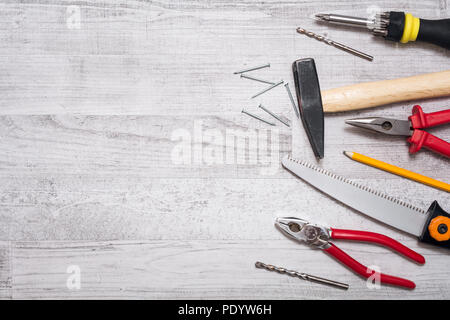 Tool Set von Hammer, Nägel, Schraubendreher, Zangen, Stift und eine Säge auf einen Holztisch - von Oben nach Unten mit Kopie Raum Stockfoto