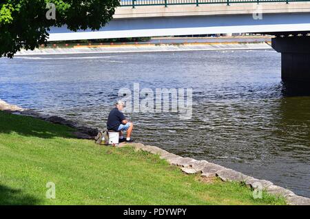 Dixon, Illinois, USA. Ein einsamer Fischer, die das Wasser des Rock River unter einer Brücke in Dicon, Illinois. Stockfoto