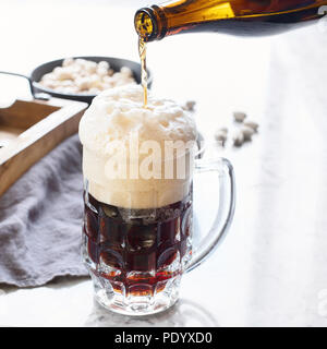 Bier zapfen aus Flasche in Glas Stockfoto