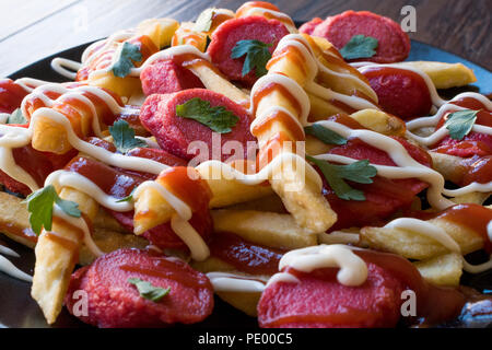 Hausgemachte peruanischen Salchipapa Pommes mit Wurstscheiben, Ketchup und Mayonnaise. Traditionelle Speisen. Stockfoto