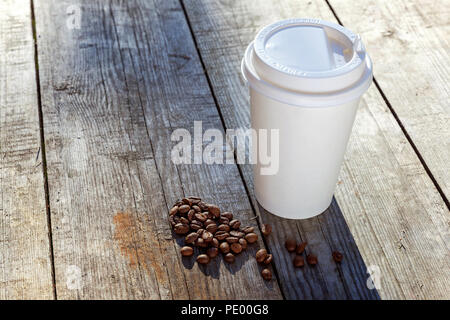 Pappbecher und Körner von Kaffee auf Holz- Hintergrund Stockfoto