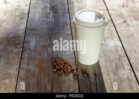 Pappbecher und Körner von Kaffee auf Holz- Hintergrund Stockfoto