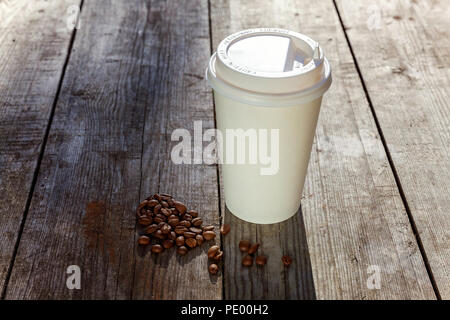 Pappbecher und Körner von Kaffee auf Holz- Hintergrund Stockfoto