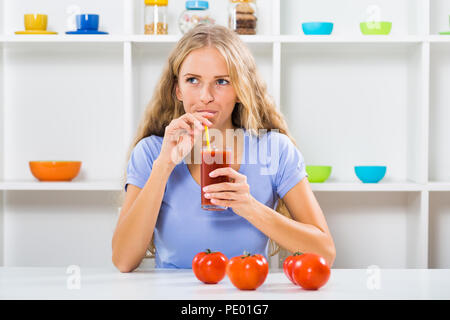 Schöne Mädchen genießt trinken Tomatensaft an ihrem Haus. Stockfoto