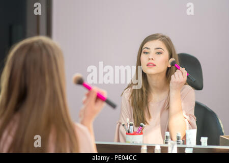 Reflexion der jungen schönen Frau, die ihr Make-up, in dem ein Spiegel Stockfoto