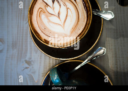 Für Sie und Ihn - zwei Tassen duftenden Kaffee und heiße Schokolade mit meisterhaften Milch Muster auf den Schaum. Eine tolle Gelegenheit, Getränke und Co genießen Stockfoto