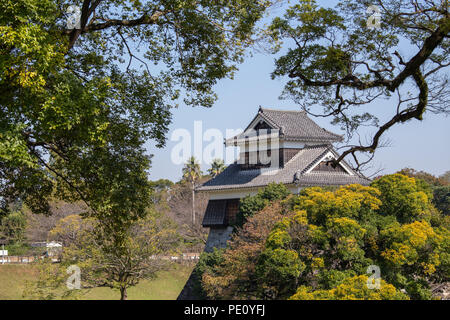 Holz- Revolver oder yagura auf stein Wand von Schloss Kumamoto in Japan umgeben von grünen Bäumen und blauer Himmel mit Kopie Raum Stockfoto