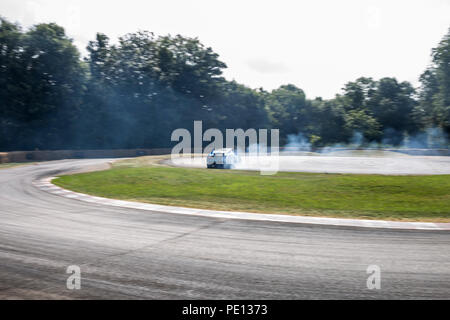 Ein Jaguar Sportwagen spinnt seine Reifen, Erstellen von Rauch, auf einer Schiene am Goodwood Festival der Geschwindigkeit 2018. Stockfoto