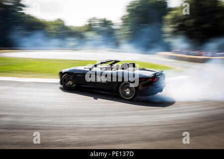 Ein Cabrio Jaguar Sportwagen spinnt seine Reifen, Erstellen von Rauch, auf einer Schiene am Goodwood Festival der Geschwindigkeit 2018. Stockfoto