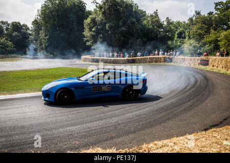 Ein Jaguar Sportwagen spinnt seine Reifen, Erstellen von Rauch, auf einer Schiene am Goodwood Festival der Geschwindigkeit 2018. Stockfoto