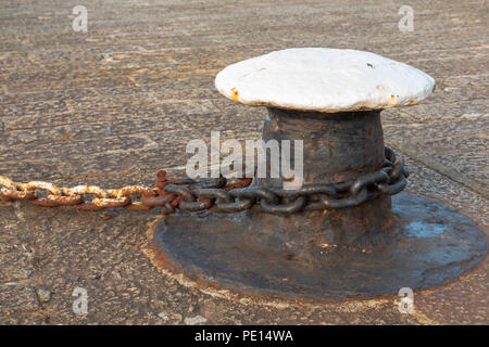 Liegeplatz Poller mit rostigen Kette befestigt, um es auf einem Kai im Hafen Stockfoto