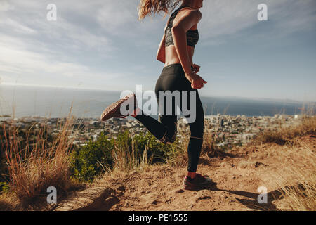 Gesunde, junge Frau, die auf Mountain Trail. Junge Frau joggen auf felsigen Weg auf einem Hügel. Stockfoto