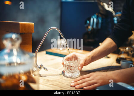 Männliche barista gießt gefiltertes Wasser in das Glas, ein Café oder eine Bar für den Hintergrund. Professionelle Kaffee Zubereitung durch den Barkeeper in der Cafeteria, Barkeeper Stockfoto