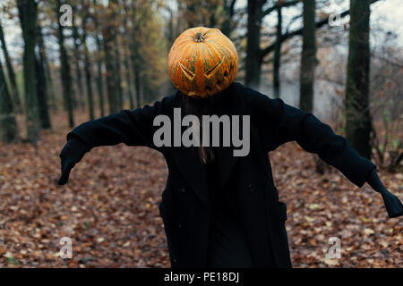 Eine schreckliche Kreatur in den Wald am Abend. Happy Halloween. Pumpkin Head. Mann mit einem Kürbis auf dem Kopf und einem schwarzen Mantel. Stockfoto