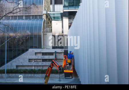 Fensterputzer in einem blauen unifor Reinigung von Windows beim Stehen auf einem Kran. In Perth, Western Australien, Ozeanien Stockfoto