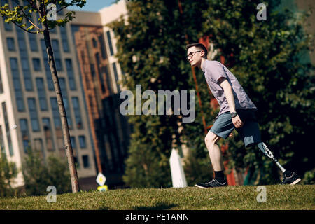 Behinderte junge Mann mit Fuß Prothese Spaziergänge im Park Stockfoto