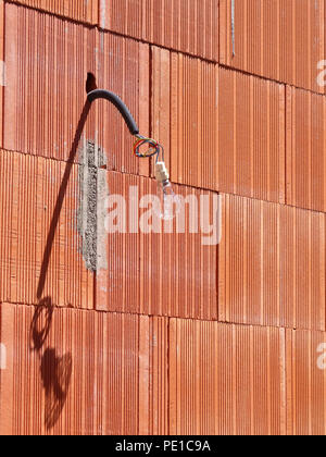 Einzelne Glühbirne hängen von einem Kabel auf der Außenseite eines neu errichteten Wand an einem Haus in Murviel-lès-Béziers, Frankreich Stockfoto