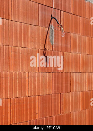 Einzelne Glühbirne hängen von einem Kabel auf der Außenseite eines neu errichteten Wand an einem Haus in Murviel-lès-Béziers, Frankreich Stockfoto