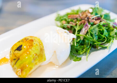 Klassische Salat mit Birne, Rucola oder rauke Blätter, gehobeltem Parmesan und Walnüsse. Beträufelt mit Olivenöl, Zitrone Essig, Burrata, gewürzt, macadamia. Stockfoto