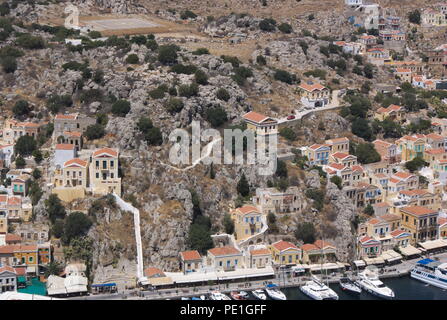 Blick auf die Häuser des Hafens von Symi Insel, Griechenland. Elegante neoklassizistische Häuser auf einem Hügel säumen die Hafenseite. Stockfoto