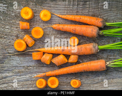 Rohe frische Karotten mit Schwänze auf alten hölzernen Hintergrund, Ansicht von oben Stockfoto