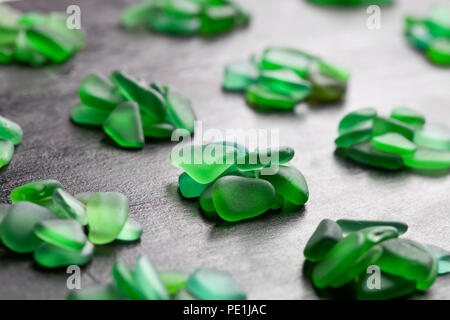 Grüne Stücke Glas poliert am Meer Nahaufnahme auf schwarzem Hintergrund Stockfoto