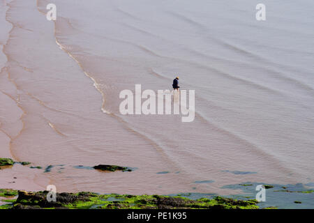 Eine Frau, die bei Ebbe im Meer paddelt. Stockfoto