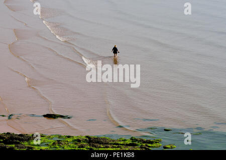 Eine Frau, die bei Ebbe im Meer paddelt. Stockfoto