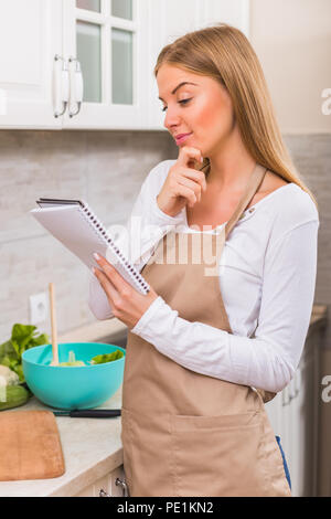Schöne Frau lesen Kochbuch während einer Mahlzeit. Stockfoto