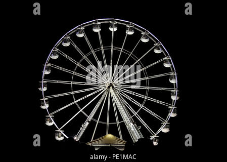 Riesenrad bei Nacht. Traditionelle Schausteller Riesenrad, Riesenrad, Fahrgeschäft mit Menschen, die Passagiere in Automobilen, Wannen, Gondeln. Stockfoto