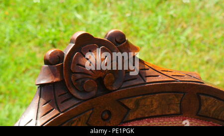 Eine einmalige Spitze eines Mahagoni holz Stuhl mit Vintage Blumenmotiven geschnitzt in es, close-up auf grünem Hintergrund Stockfoto