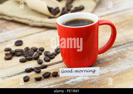 Guten Morgen Karte mit roten Becher Kaffee, verstreute Kaffeebohnen auf Holzmöbeln im Landhausstil Oberfläche Stockfoto