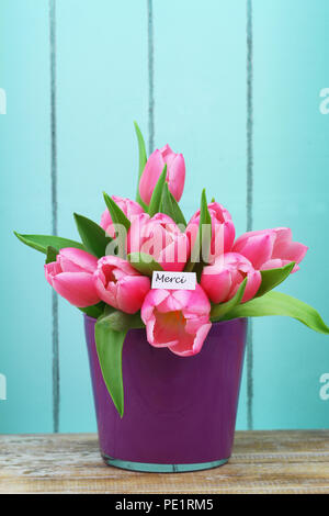 Merci (vielen Dank, dass Sie sich in Französisch) Karte mit rosa Tulpen im Topf Stockfoto