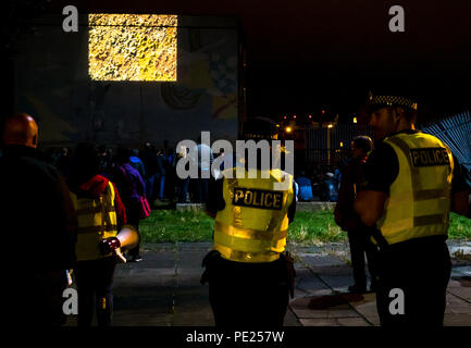 Schottland, Großbritannien. August 2018. Leith, Edinburgh Fringe Festival Outdoor-Event, Schottland, Großbritannien. Eine Wand ist eine Leinwand: Kostenlose geführte Kurzfilmwanderung mit standortspezifischen Außenvorführungen an Gebäudewänden bei einer Führung durch fünf Orte in den hinteren Straßen von Leith. Zu den Orten gehörten der soziale Wohnblock Linksview, Die Water Street und The Shore. Die Gemeinschaftspolizei eskortierte die große Menschenmenge und berichtete, dass rund 600 Personen an der Veranstaltung teilnahmen Stockfoto