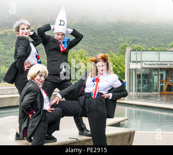 Edinburgh, Schottland, Großbritannien. 12. August 2018. Edinburgh Fringe Festival Fotoshooting auf einem trostlosen schottische Wetter Tag, Schottische Parlament, Holyrood Edinburgh, Edinburgh, Schottland, Vereinigtes Königreich. Politischen Clowns in Silly stellt außerhalb des Parlaments. Schwein Circus ist als 'Verbatim Brexit Parodie' über den Umgang der Regierung mit Brexit Verhandlungen in Rechnung gestellt, mit Zeichen Teresa kann, Boris Johnson, David Davies und Liam Fox in einer nacherzählung von Lieblingsthema der Nation. Durch die Theatergruppe Hitchhiker Kollektive produziert Stockfoto