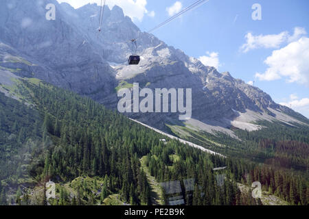 Zugspitze, Deutschland. 19. Juli 2018. Eine Seilbahn von der Seilbahn auf die Zugspitze können auf das Bergmassiv der Zugspitze von der Talstation gesehen werden. Mit 2962 Metern über dem Meeresspiegel, die Zugspitze ist der höchste Gipfel des Wettersteingebirges und gleichzeitig den höchsten Berg Deutschlands. Die Tiroler Zugspitzbahn ist eine Seilbahn vom Hotel settlement Ehrwald-Zugspitzbahn (Ehrwald-Obermoos) an die westlichen Gipfel der Zugspitze. - Keine LEITUNG SERVICE-Credit: Alexandra Schuler/dpa/Alamy leben Nachrichten Stockfoto