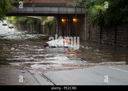 Liverpool, Großbritannien. 12 August, 2018. UK Wetter. Junge Paare sind in Ihrem Auto eingeschlossen, nachdem Überschwemmungen Liverpool schlagen. Die Paare wurden auf Queens Drive L 18 auf einem berüchtigten Sprung in der Straße gefangen, nach dem Kampf gegen das steigende Wasser sie schließlich durch das Wasser wateten gerade als die Feuerwehr eintraf. Credit: Ken Biggs/Alamy Leben Nachrichten. Stockfoto