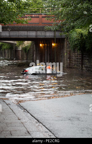 Liverpool, Großbritannien. 12 August, 2018. UK Wetter. Junge Paare sind in Ihrem Auto eingeschlossen, nachdem Überschwemmungen Liverpool schlagen. Die Paare wurden auf Queens Drive L 18 auf einem berüchtigten Sprung in der Straße gefangen, nach dem Kampf gegen das steigende Wasser sie schließlich durch das Wasser wateten gerade als die Feuerwehr eintraf. Credit: Ken Biggs/Alamy Leben Nachrichten. Stockfoto