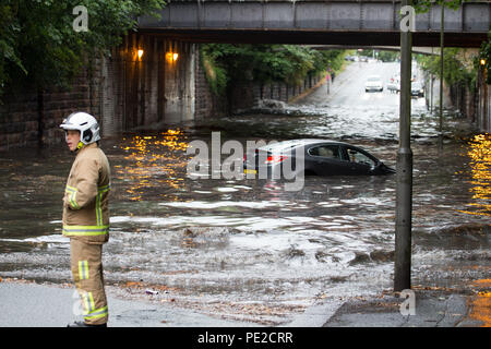 Liverpool, Großbritannien. 12 August, 2018. UK Wetter. Junge Paare sind in Ihrem Auto eingeschlossen, nachdem Überschwemmungen Liverpool schlagen. Die Paare wurden auf Queens Drive L 18 auf einem berüchtigten Sprung in der Straße gefangen, nach dem Kampf gegen das steigende Wasser sie schließlich durch das Wasser wateten gerade als die Feuerwehr eintraf. Credit: Ken Biggs/Alamy Leben Nachrichten. Stockfoto