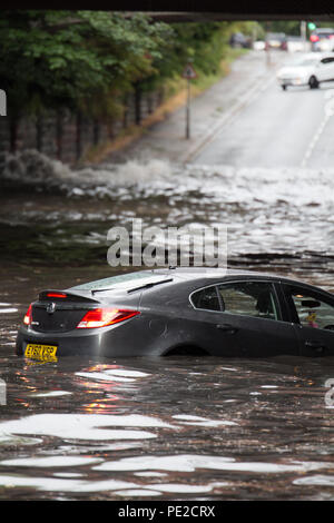 Liverpool, Großbritannien. 12 August, 2018. UK Wetter. Junge Paare sind in Ihrem Auto eingeschlossen, nachdem Überschwemmungen Liverpool schlagen. Die Paare wurden auf Queens Drive L 18 auf einem berüchtigten Sprung in der Straße gefangen, nach dem Kampf gegen das steigende Wasser sie schließlich durch das Wasser wateten gerade als die Feuerwehr eintraf. Credit: Ken Biggs/Alamy Leben Nachrichten. Stockfoto