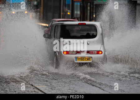 Liverpool, Großbritannien. 12 August, 2018. UK Wetter. Autos fahren durch Überschwemmungen auf Smithdown Road, Liverpool, 15 nach dem sintflutartigen Regen die Straße überflutet. Credit: Ken Biggs/Alamy Leben Nachrichten. Stockfoto