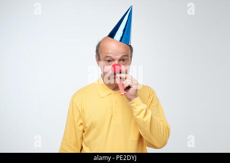 Unglücklich geburtstag Kerl mit Stoppeln traurig und enttäuscht, weil niemand kam, um seinen Geburtstag zu feiern, Blasen party Horn ganz allein Stockfoto