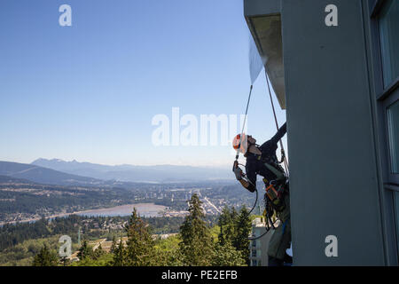 Burnaby Mountain, Vancouver, British Columbia, Kanada - Juli 011, 2018: Hohes Seil Glasreiniger ist Macht Waschen das Gebäude während eines Ho Stockfoto